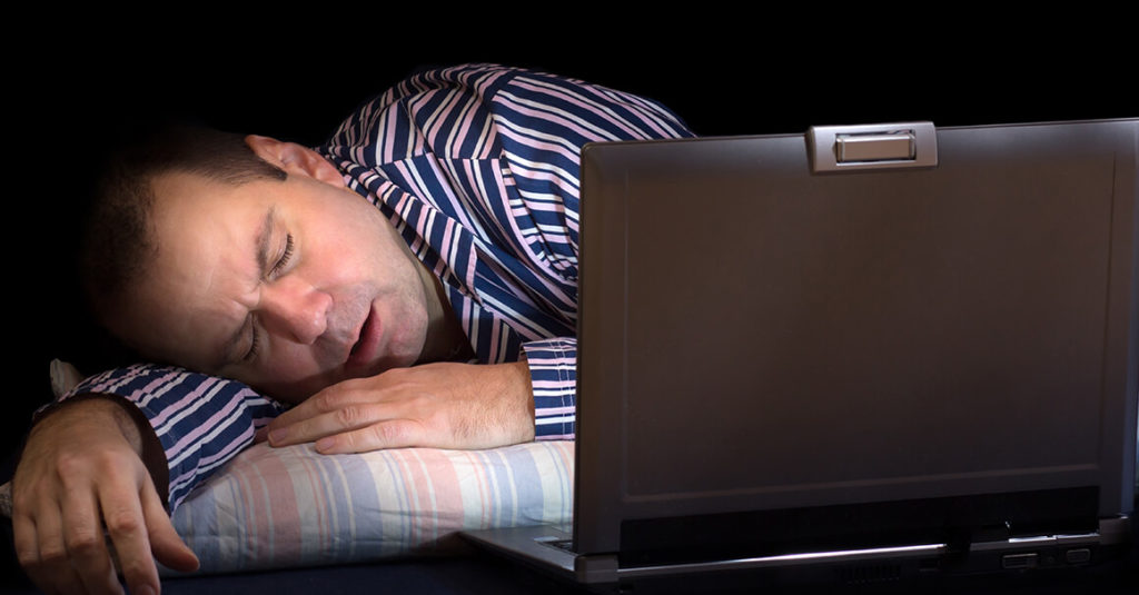 a man asleep in front of a computer